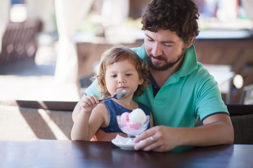 Father and daughter eating ice cream at the restaurant