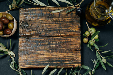 Healthy snack: Dark and green olives, oil, goat cheese on a wooden board, space for text