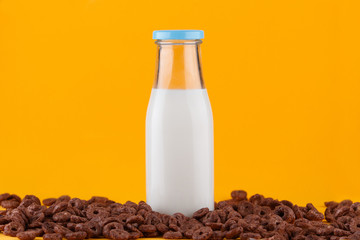 Chocolate cereals and milk bottle on yellow  background