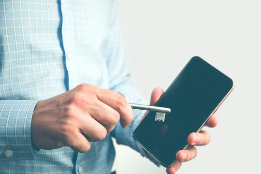 Man holding phone and old key. Trying to open, hack, crack phone. Cyber security.