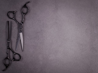Hairdresser tools for hair styling on dark gray background top view space for text.