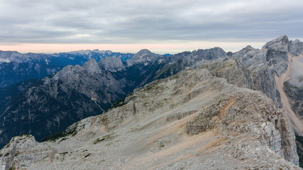 Sheer mountain cliff with slope on one side.