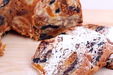 isolated traditional christmas stollen cake, sweet german bread, with dried fruits on wooden background