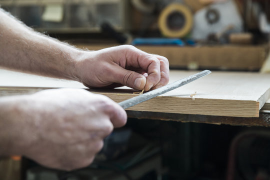 Carpenter hands using a file to finish a piece of wood