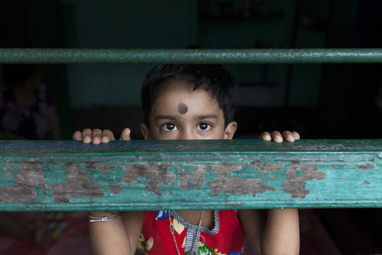 Little girl behing the window and looking at camera