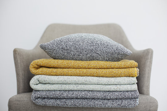 Set of folded blankets and pillow on a chair