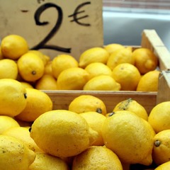 Fresh lemons for sales ion wooden boxes on a French market stall, with price ticket of 2 Euros
