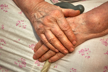 wrinkled skin of the hands of an senior woman with a cane