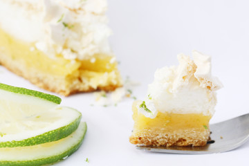 eating bite of piece of fresh baked lemon meringue pie, tart, decorated with lime, isolated on white