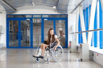 A young girl in a wheelchair is standing in the corridor of the hospital.