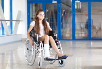 A young girl in a wheelchair is standing in the corridor of the hospital.