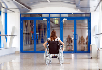 A young girl in a wheelchair is standing in the corridor of the hospital.