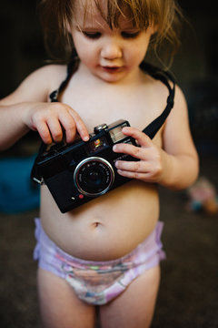 Toddler girl playing with an old camera