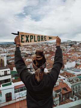 Person stands holding an Explore" flag overlooking the city skyline of Madrid""erson stands holding an "Explore" flag overlooking t""rson stands holding an "Exp""son"