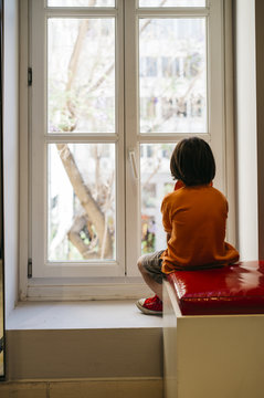 5 year old boy looking outside of a window