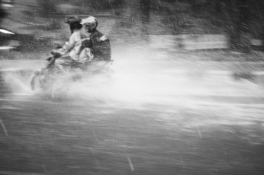 Two in the motorbike driving through the heavy rain
