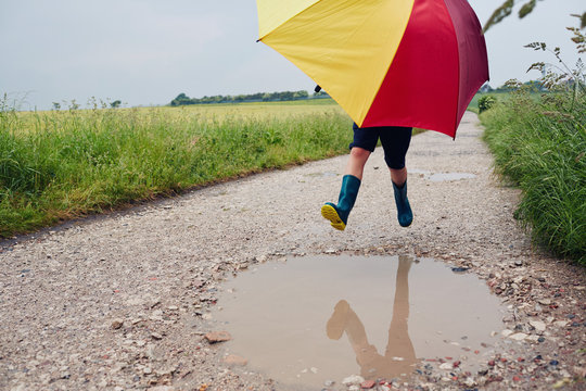 Child having fun playing outdoors on a rainy day with an umbrella
