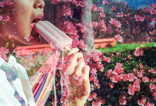 Pretty asian girl eating a pink popsicle on a warm summer day surrounded by pink flowers