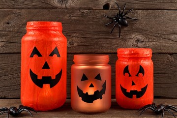 Mason jar Halloween Jack o Lanterns against an old wood background