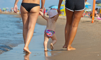 Mom teaches her daughter to walk to the beach.