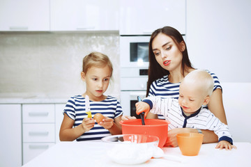 Obraz na płótnie Canvas Adorable happy family makes cakes together on your white kitchen.