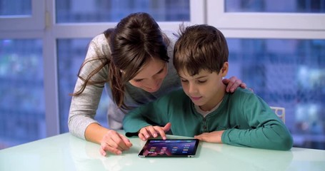 Mother and son child use a tablet 4k video. Woman parent and boy kid touch mobile PC screen. Family and technology - Powered by Adobe