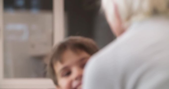 Grandson kid hugging grandmother at home HD slow-motion video. Child boy running to old woman. Close-up of smiling face. Grandparents and grandchildren love