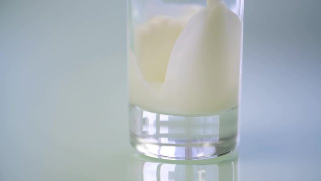 Milk pouring into glass HD isolated close-up slow-motion video. Milk falling and splashing. Morning breakfast beverage concept