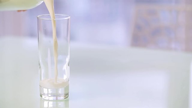 Milk pouring into glass HD isolated close-up slow-motion video with copy space. Milk falling and splashing. Morning breakfast beverage concept