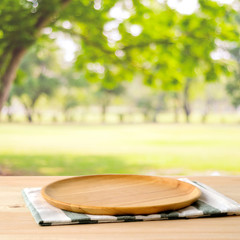 Empty wooden tray on table over blur green park background, food display montage, food background