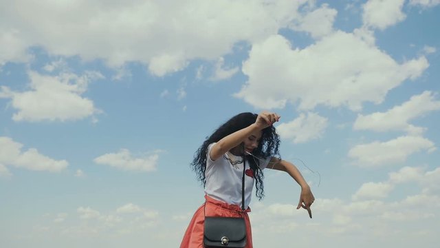 Curly brunette dancing to music and suddenly drops a phone