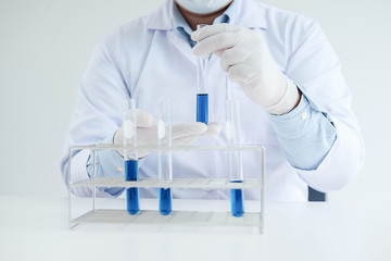 Fototapeta premium Medical or scientific researcher or man doctor looking at a test tube of clear solution in a laboratory