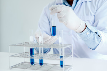 Medical or scientific researcher or man doctor looking at a test tube of clear solution in a laboratory