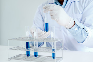 Fototapeta premium Medical or scientific researcher or man doctor looking at a test tube of clear solution in a laboratory