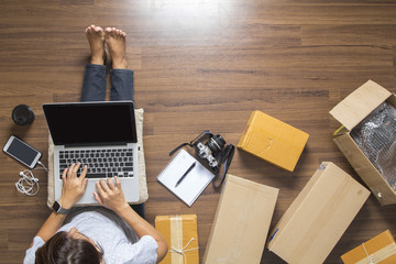 Top view of women working laptop computer from home on wooden floor with postal parcel, Selling...