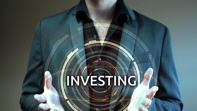 A businessman holds up a futuristic glowing aura reading Investing