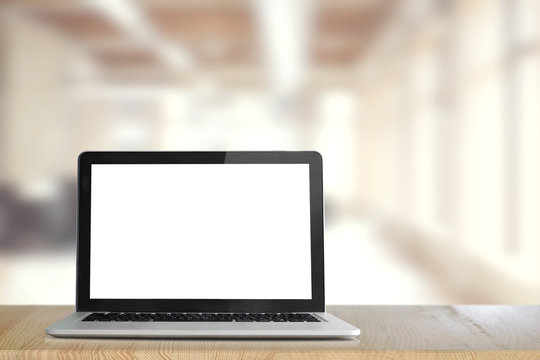 Mock up Blank screen of Laptop on wood table in Co-working or office.