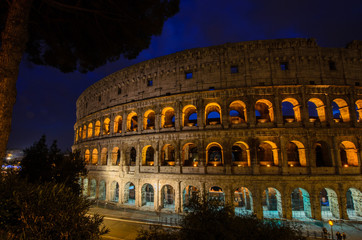 Fototapeta na wymiar Colosseum or Coliseum at night, Rome, Italy. Roman Colosseum is one of top travel attraction in Europe. Famous ancient architecture in central Rome. Night panoramic view of Rome landmark in lights.