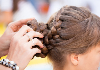 Naklejka premium the stylist weaves the female braids on the head