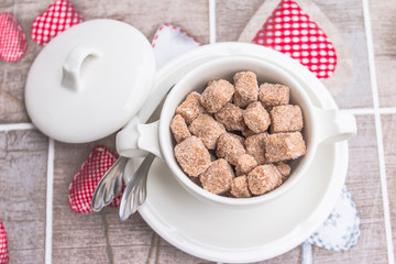  brown sugar cane cube in white bowl  with silverware on table. Close up image.  Top view. Good sweet tasty morning concept
