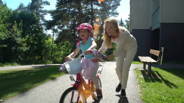 First cycling. Mother teaches her daughter to ride a bicycle.
