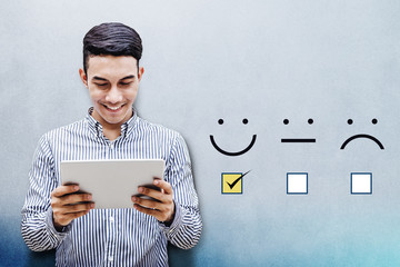 Customer Experience Concept, Happy Businessman holding digital Tablet with a checked box on Excellent Smiley Face Rating for a Satisfaction Survey - obrazy, fototapety, plakaty