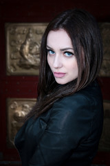 Fototapeta premium beautiful girl, brunette with blue eyes, wearing a leather jacket on a dark background