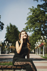 Young beautiful woman talking on the phone sitting in park