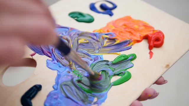 Painter hands blending vivid colors on the palette. 4K.