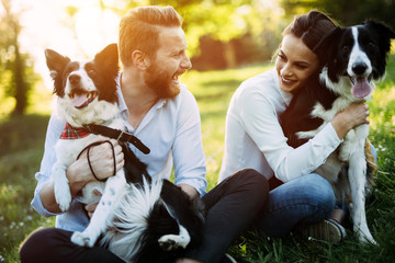 Romantic couple in love walking dogs in nature and smiling