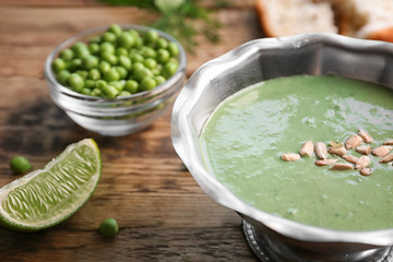 Delicious puree from green peas in bowl on wooden table