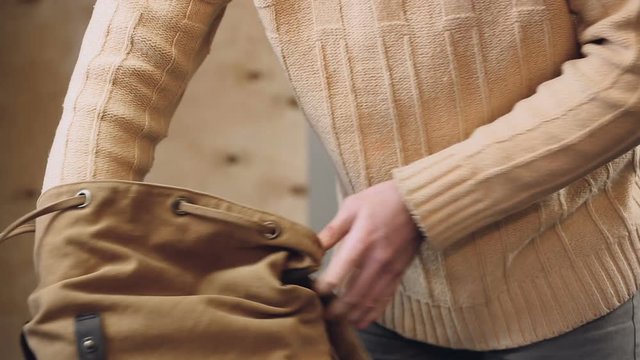 Furious man turning his backpack upside down searching for necessary thing