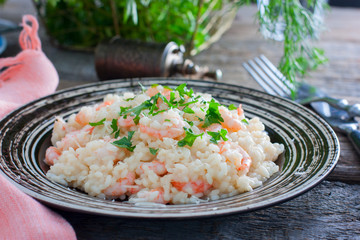 Italian risotto with shrimps on a table with fresh herbs, horizontal