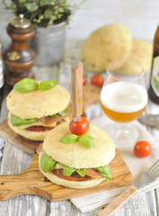 a hamburger with a meat chop and beer, decorated with fresh herbs and cherry tomatoes